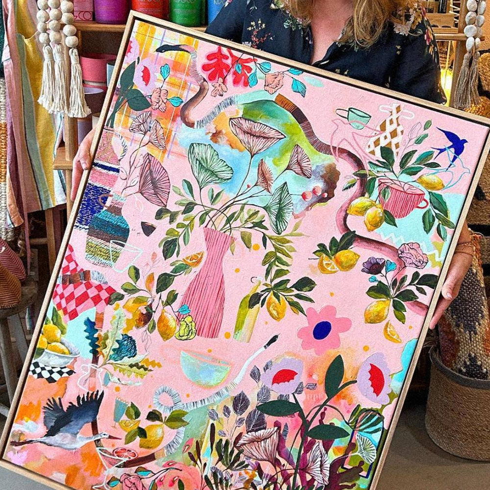 Person holding a colorful painting in a store setting with various items in the background