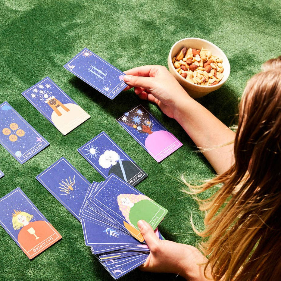 Person playing a card game with tarot cards on a green surface